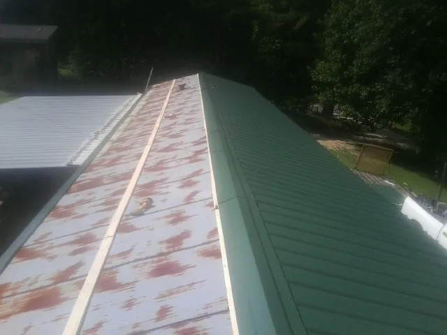 Old rusted panels beside newly installed green metal roofing — Wind Damage Roof Repair by Roofing Brothers in Matteson