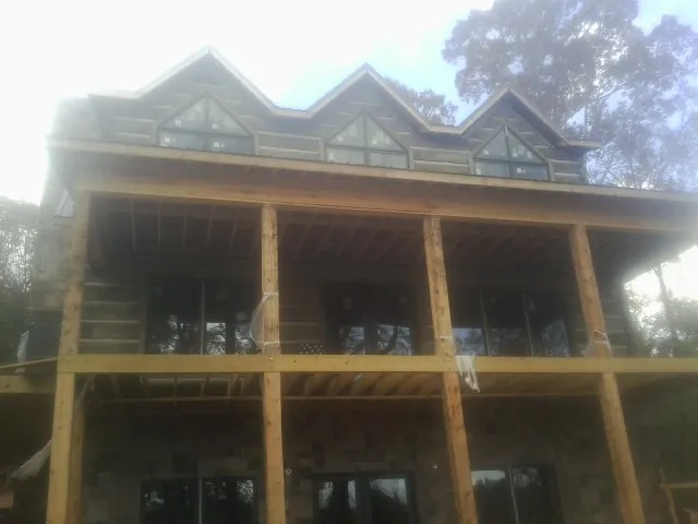 Dormers and porch framing on a large log home under construction — Roof Coating work by our crew in Matteson