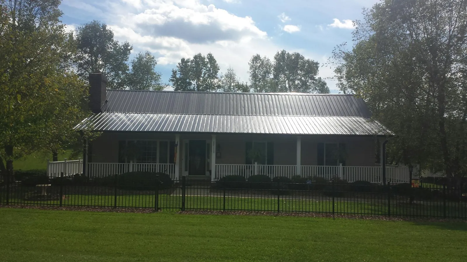 Gray metal roof on a brick ranch with a full width front porch — Gutter Guard Installation work by our crew in Matteson