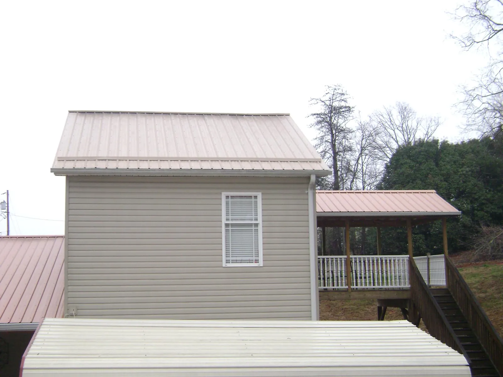 Tan metal roofs on a two story addition and attached porch, from a Roof Replacement job in Matteson