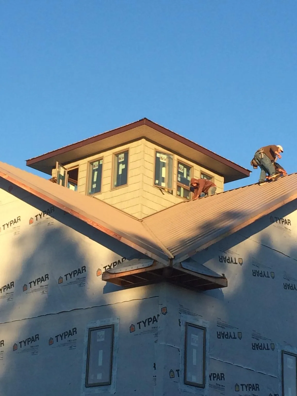 Roofers working around a rooftop cupola on a new metal roof at sunset — Roof Waterproofing in Matteson by Roofing Brothers